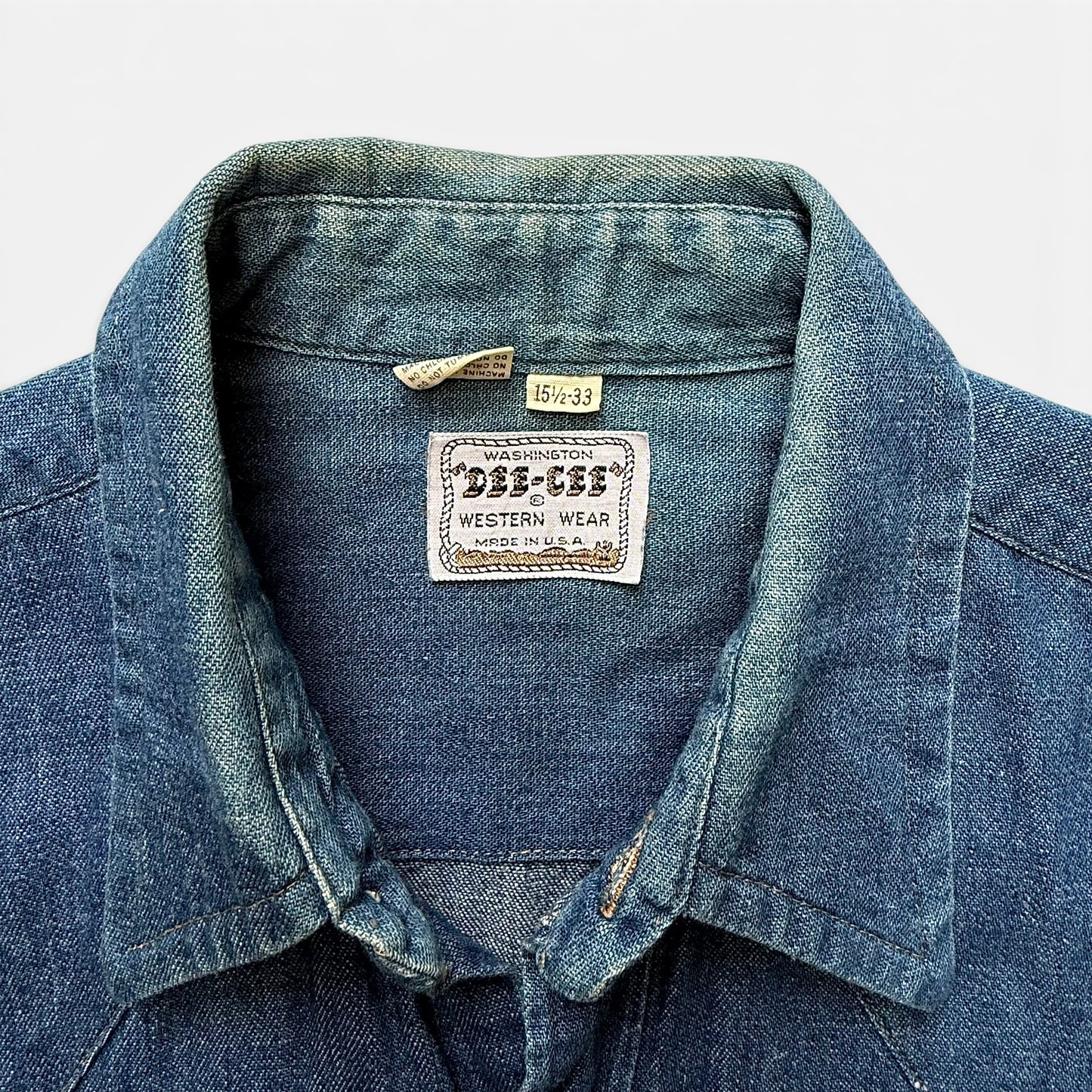1960s Dee Cee Denim Sawtooth Western Shirt Close-up of a denim shirt with a label on a white background