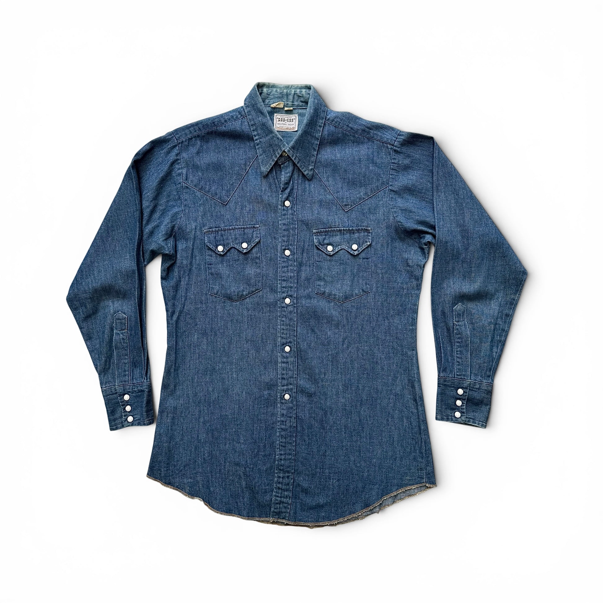 1960s Dee Cee Denim Sawtooth Western Shirt Blue denim shirt with button details on a white background