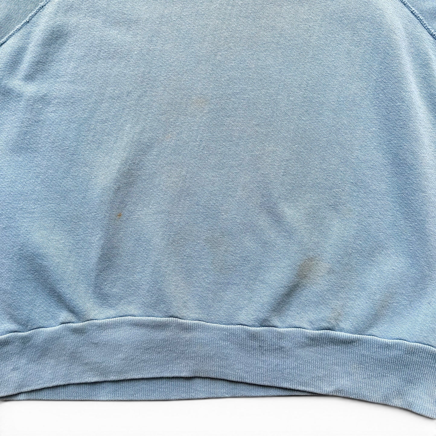 1960s Indian Motorcycles Short Sleeve Sweatshirt Close-up of a blue fabric surface with visible stains.