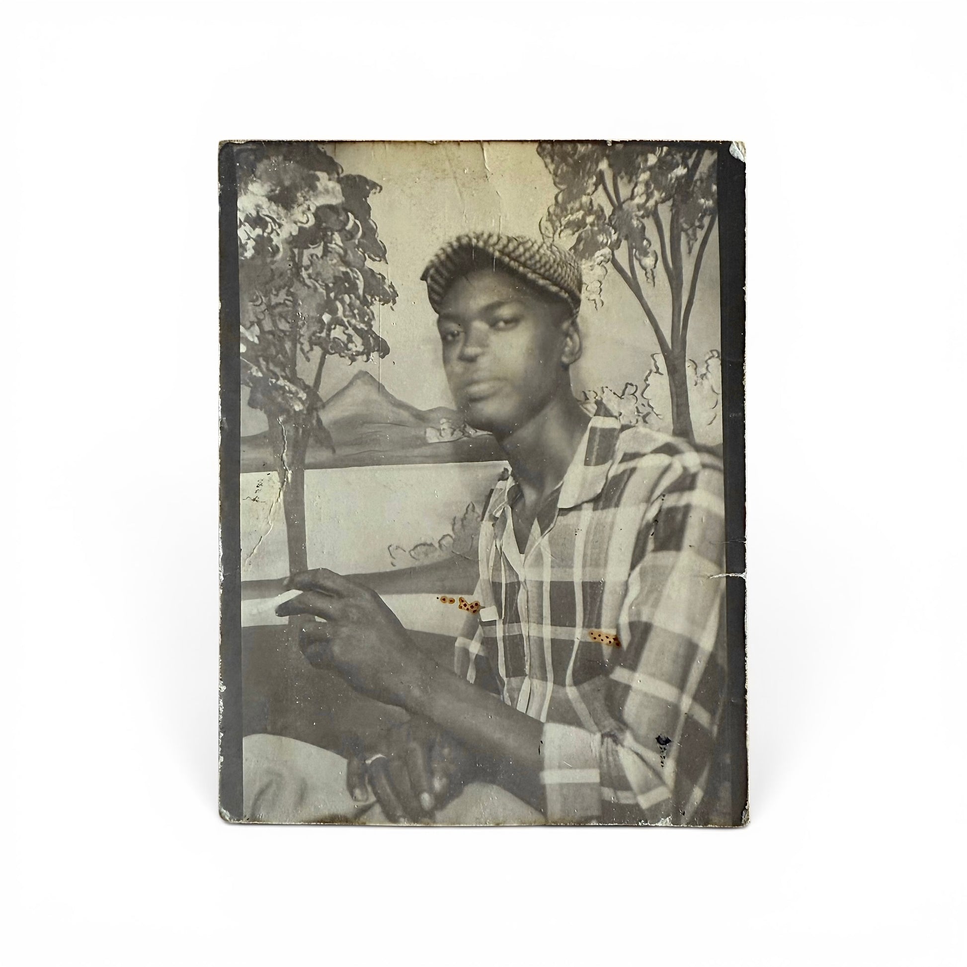 Vintage photo booth photo with an african american man holding a cigarette against a scenic background