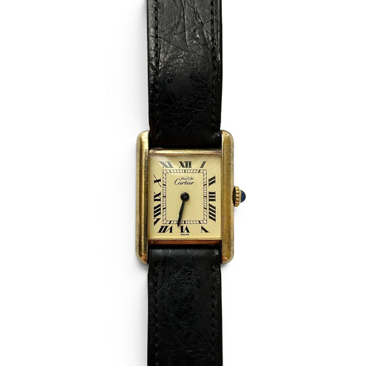 Late 1970s Must De Cartier Manual Wind Tank Watch Cartier watch with black strap on a white background