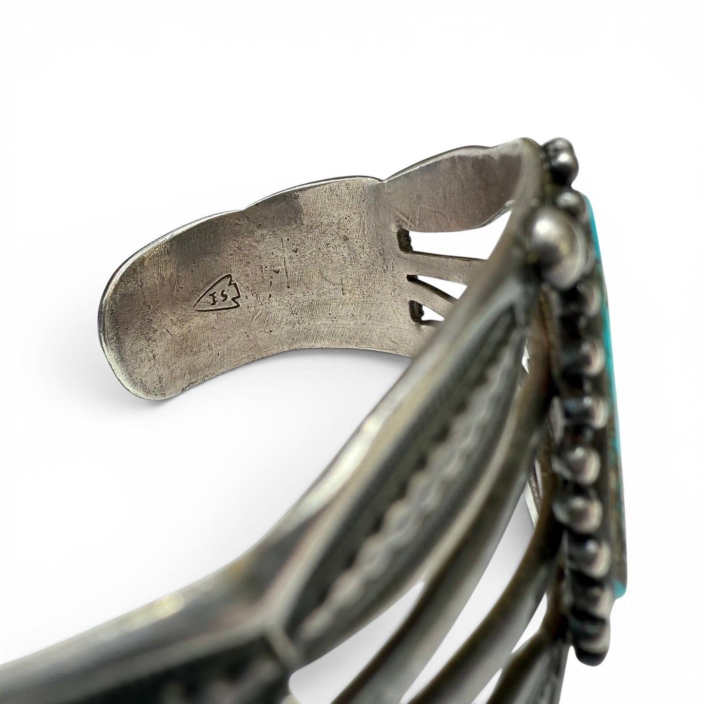 Vintage Sterling Silver & Turquoise Diné (Navajo) Bracelet Close-up of a silver bracelet with intricate design on a white background